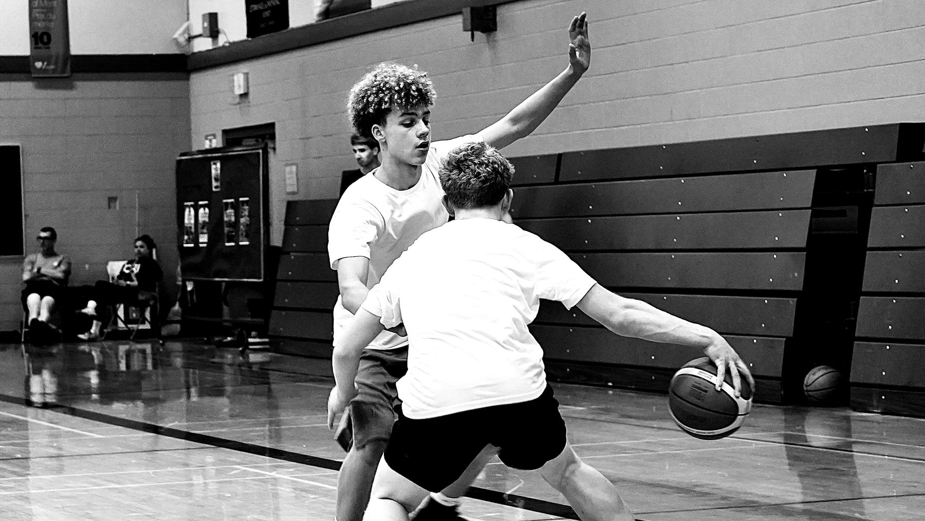 A defender pressures a ball handler going baseline