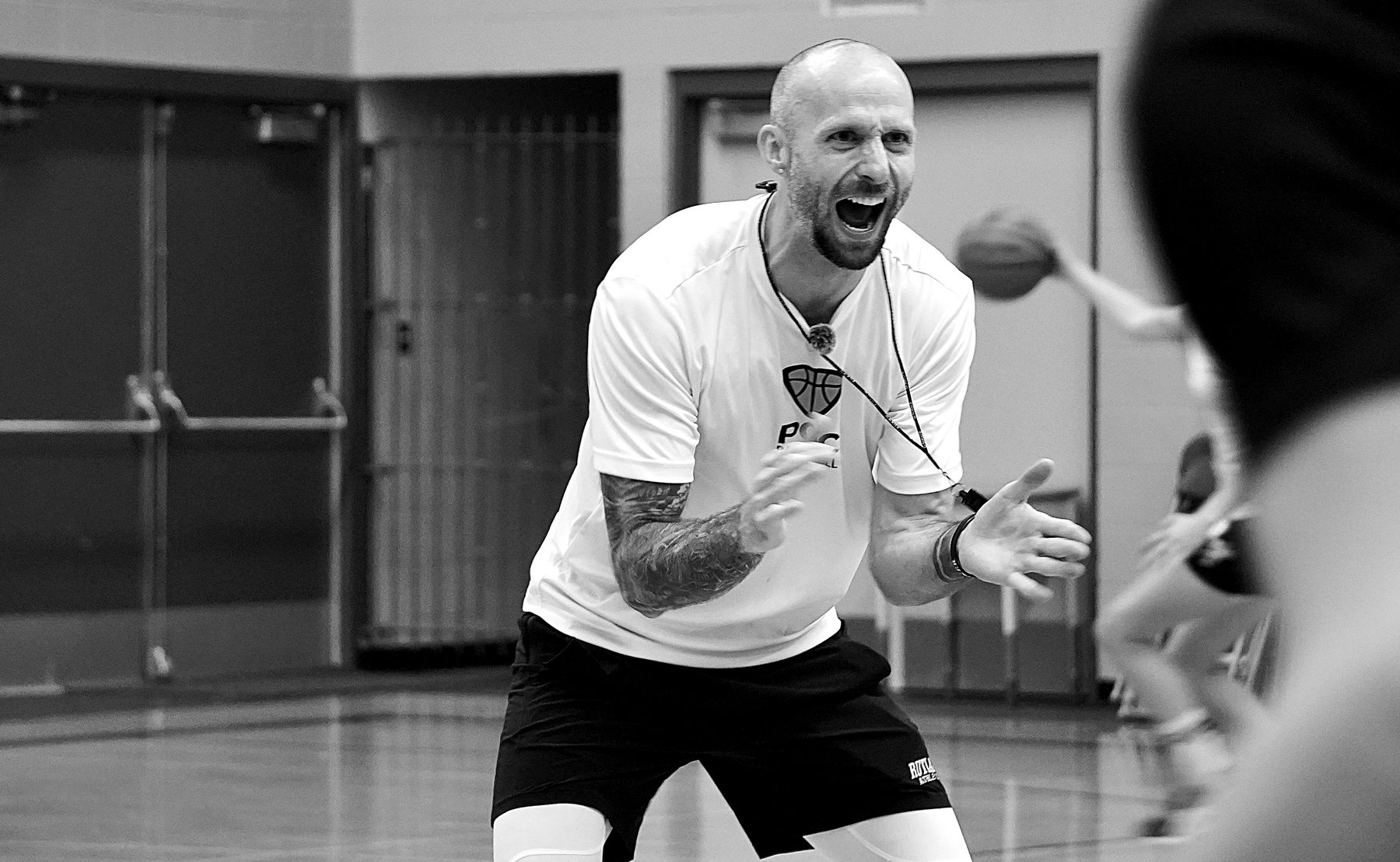 Coach Tyler Lutton coaching on the court, mid-instruction
